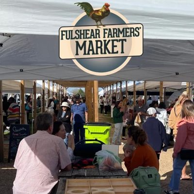 People gathered under tents at Fulshear Farmers' Market, with a sign featuring a chicken above.